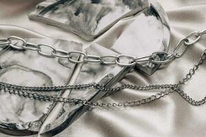 élégant argent chaîne bijoux sur le cou sur une soie brillant Contexte. photo