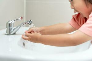 peu enfant mains laver avec savon bulles et rincer avec nettoyer l'eau à prévenir et Arrêtez le propager de germes après retour à maison, virus ou COVID-19 [feminine. bien santé et bien personnel hygiène, virus, les bactéries photo