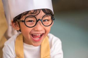 portrait mignon petit garçon heureux asiatique intéressé par la cuisine avec la mère drôle dans la cuisine à domicile. les modes de vie et la famille des gens. concept de nourriture et d'ingrédients faits maison. cuisson du gâteau de noël et des biscuits photo