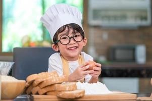 portrait mignon petit garçon de bonheur asiatique intéressé par la boulangerie avec drôle dans la cuisine à domicile. les modes de vie et la famille des gens. concept de nourriture et d'ingrédients faits maison. cuisson du gâteau de noël et des biscuits photo