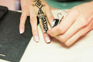 Jeune femme mehendi artiste La peinture henné sur le main photo