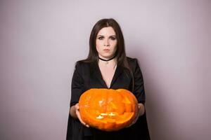 femme comme sorcière est permanent avec le citrouille dans le studio. Halloween et carnaval concept photo