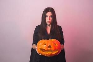 gothique Jeune femme dans sorcière Halloween costume avec une sculpté citrouille photo