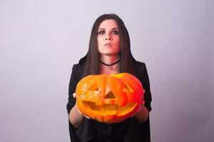 femme comme sorcière est permanent avec le citrouille dans le studio. Halloween et carnaval concept photo