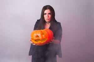 Halloween sorcière en portant une Orange citrouille jack o lanterne avec fumée photo