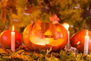 Halloween citrouille lanterne avec sec feuilles, bougies et fumée photo