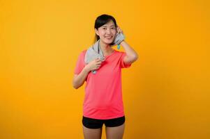 portrait Jeune asiatique des sports aptitude femme content sourire portant rose tenue de sport et visage serviette Faire exercice formation faire des exercices contre Jaune studio Contexte. bien-être et en bonne santé mode de vie concept. photo