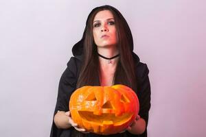 Jeune femme dans Halloween sorcière costume dans studio avec Jaune citrouille. photo