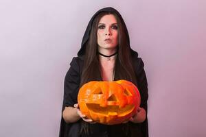 Jeune femme dans Halloween sorcière costume dans studio avec Jaune citrouille. photo