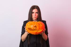 gothique Jeune femme dans sorcière Halloween costume avec une sculpté citrouille photo