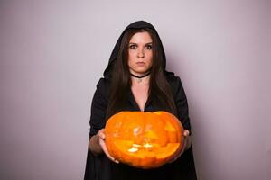 Jeune femme dans Halloween sorcière costume dans studio avec Jaune citrouille. photo