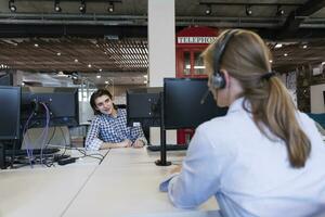 une femme dans une casque parlant à une homme à une bureau photo