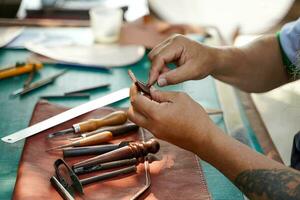 fermer et surgir mains de cuir artisan est travail difficile à Coudre une cuir produit pour une client. photo