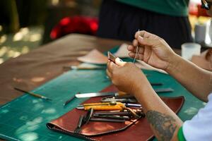fermer main de cuir artisan est soigneusement à Coudre une cuir ceinture pour une client., cuir artisan concept. photo