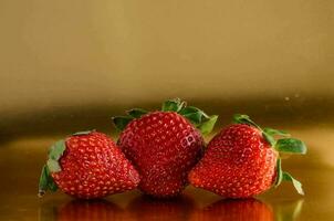 Trois des fraises sur une or Contexte photo