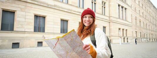 roux fille, touristique explore ville, regards à papier carte à trouver façon pour historique Repères, femme sur sa voyage autour Europe recherches pour tourisme photo