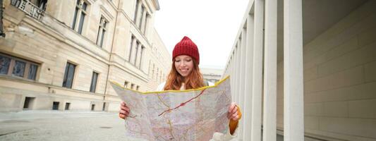 roux fille, touristique explore ville, regards à papier carte à trouver façon pour historique Repères, femme sur sa voyage autour Europe recherches pour tourisme photo