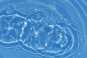 l'eau bleue bulles sur le surface ondulations. défocalisation flou transparent blanc noir coloré clair calme l'eau surface texture avec éclaboussure et bulles. l'eau vagues avec brillant modèle texture Contexte. photo