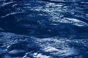l'eau bleue bulles sur le surface ondulations. défocalisation flou transparent blanc noir coloré clair calme l'eau surface texture avec éclaboussure et bulles. l'eau vagues avec brillant modèle texture Contexte. photo