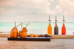 fruit des cocktails dans des lunettes avec noix de coco boisson avec bambou pailles sur une plage, l'eau bord et mer voir. concept de luxe vacances. gratuit espace pour La publicité texte photo