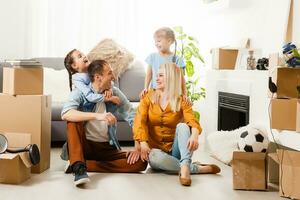 content famille avec papier carton des boites dans Nouveau maison à en mouvement journée. photo