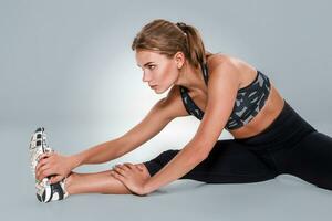 élongation faire des exercices posture par une femme sur studio gris Contexte photo