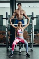 sport, aptitude, travail en équipe, la musculation et gens concept - Jeune femme et personnel entraîneur avec haltère fléchissement muscles dans Gym photo
