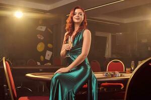 Jeune magnifique femme est posant contre une poker table dans luxe casino. photo