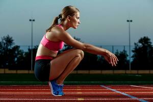 image de magnifique Jeune européen femelle coureur ou sprinter séance sur Extérieur stade piste, sentiment épuisé après sprint ou marathon. photo