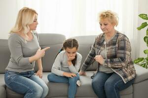 frustré fille séance à Accueil tandis que mère et grand-mère réprimander sa photo