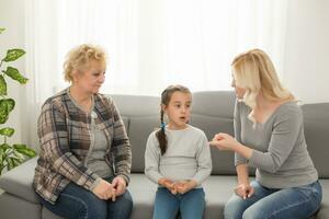 frustré fille séance à Accueil tandis que mère et grand-mère réprimander sa photo