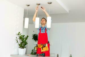 électricien est installation et de liaison une lampe à une plafond. photo