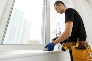 ouvrier dans installation caoutchouc scellés sur Plastique upvc la fenêtre. photo