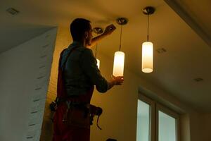 électricien est installation et de liaison une lampe à une plafond. photo