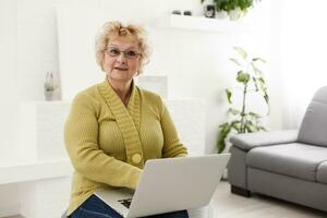 content personnes âgées femme en utilisant portable ordinateur à Accueil photo