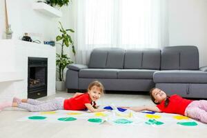 deux content les filles dans enfants vêtements avec enthousiasme jouer sur le sol. photo