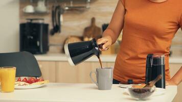 femme verser chaud café dans tasse dans le Matin de pot. femme au foyer à Accueil fabrication Frais sol café dans cuisine pour petit-déjeuner, en buvant, broyage café Expresso avant Aller à travail photo