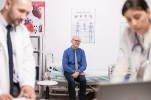 effrayé Sénior patient attendre pour diagnostic de équipe de médecins dans hôpital Bureau après examen. vieux homme pendant médical vérifier en haut. médecins dans blanc manteau. photo