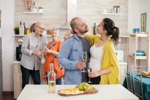 couple à la recherche à chaque autre dans cuisine pendant famille brunch. homme en portant verre de du vin. apéritif avec divers fromage. photo