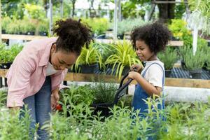 la mère et la fille africaines choisissent des plantes de légumes et d'herbes de la pépinière du centre de jardinage local avec un panier rempli de plantes d'été pour le jardinage du week-end et en plein air photo