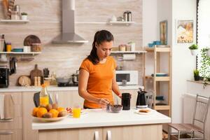 femme en mettant café des haricots dans broyeur dans le Matin. femme au foyer à Accueil fabrication Frais sol café dans cuisine pour petit-déjeuner, en buvant, broyage café Expresso avant Aller à travail photo