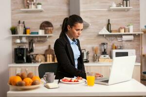 concentré affaires femme travail à portable de Accueil dans le cuisine. pigiste dans le Matin multitâche dans le cuisine avant Aller à le bureau, stressant façon de vie, carrière et buts à rencontrer. photo