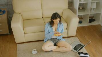 Haut vue de femme dans court jeans en train de lire une livre avec une tasse de café et une portable suivant à sa photo