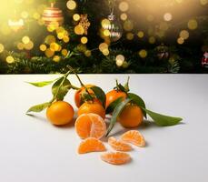 Frais mandarines avec vert feuilles sur une blanc tableau. là est une Noël arbre avec jouets dans le Contexte. Nouveau années Contexte. photo
