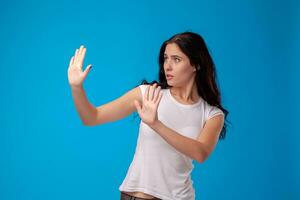 studio portrait de une Jeune magnifique femme dans une blanc T-shirt contre une bleu mur Contexte. gens sincère émotions. photo