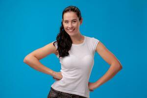 studio portrait de une Jeune magnifique femme dans une blanc T-shirt contre une bleu mur Contexte. gens sincère émotions. photo