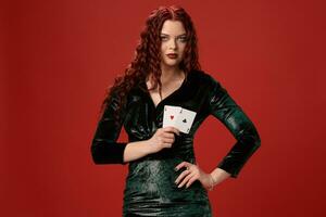 Jeune sexy femme avec une rouge frisé cheveux en portant as, sur une rouge Contexte. poker photo