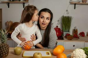 mère et sa fille sont Faire une fruit Coupe et ayant amusement à le cuisine. photo