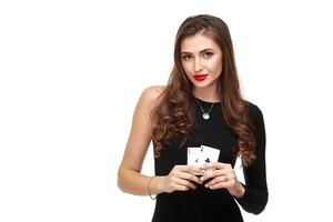 sexy frisé cheveux brunette posant avec deux as cartes dans sa mains, poker concept isolement sur blanc Contexte photo