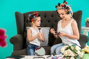 maman et fille dans le studio sur le canapé dans le bigoudis faire en haut et avoir amusement photo